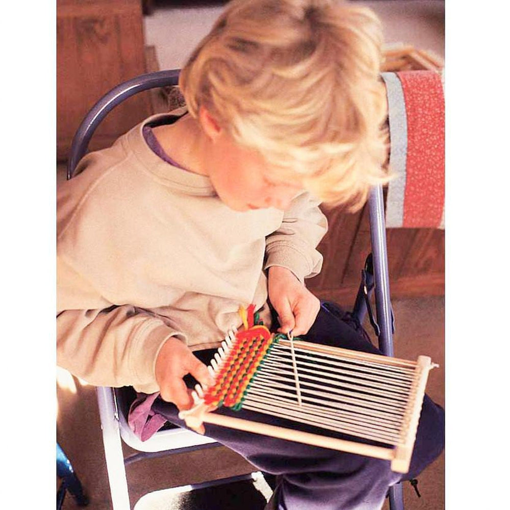 Chłopiec i dziewczynka naprawiają splot na krośnie pod kierunkiem dorosłego