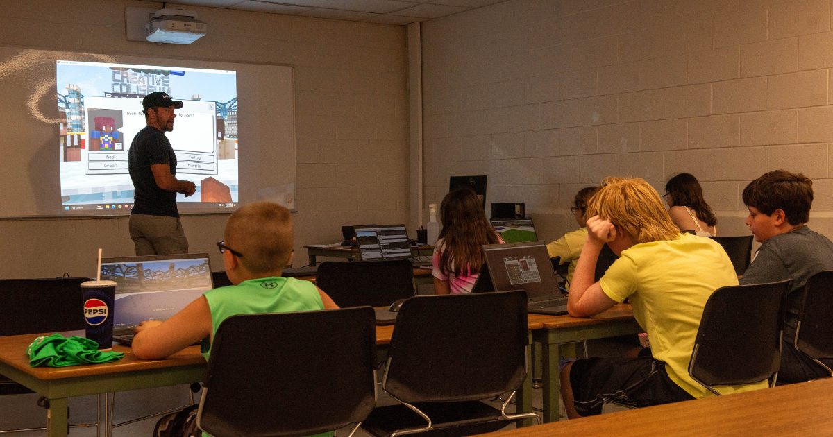 Miejsce pracy nad cyfrowymi projektami Grupa uczestników używa komputerów w sali obozowej Minecraft